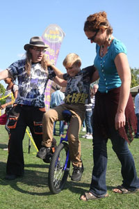 parent helping child on unicycle